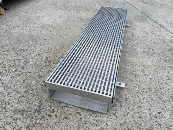 Photo of a stainless steel trench drain on concrete